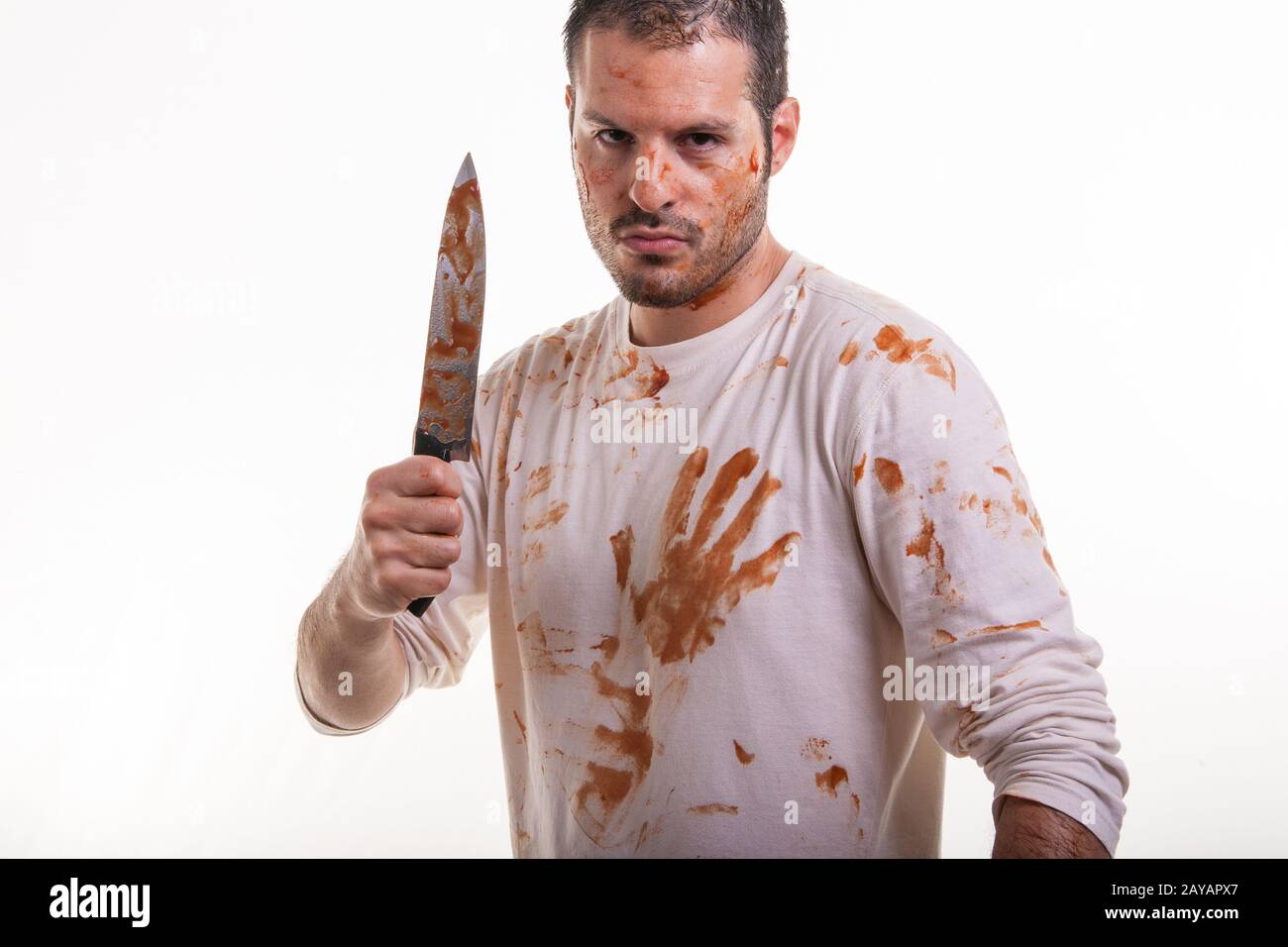 A bloody scene with a man and a blood-covered knife in his hand isolated on white background. Violence and Halloween concept. Stock Photo