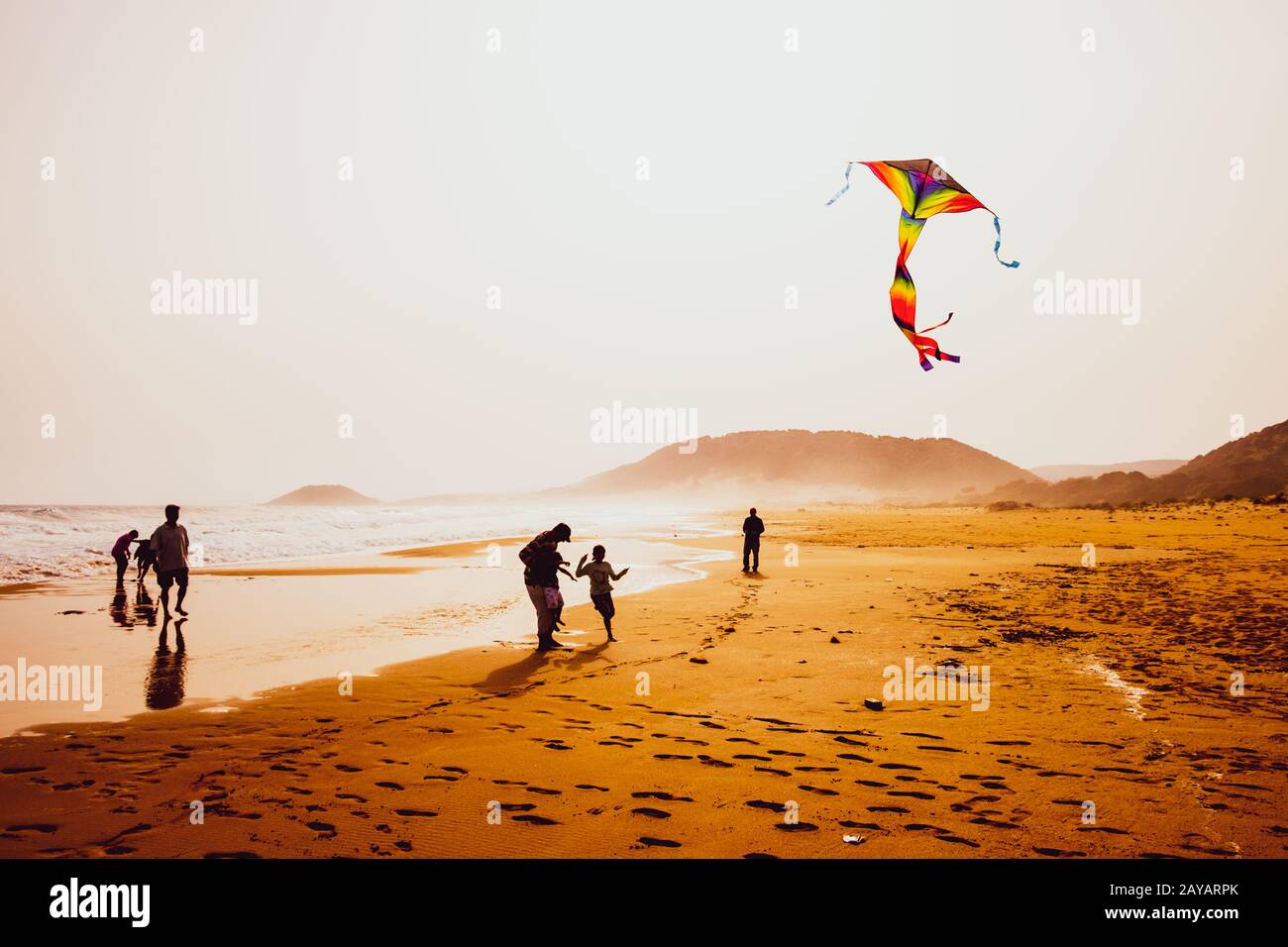 Silhouettes of people playing and flying a kite in sandy Golden Beach, Karpasia, Cyprus Stock Photo