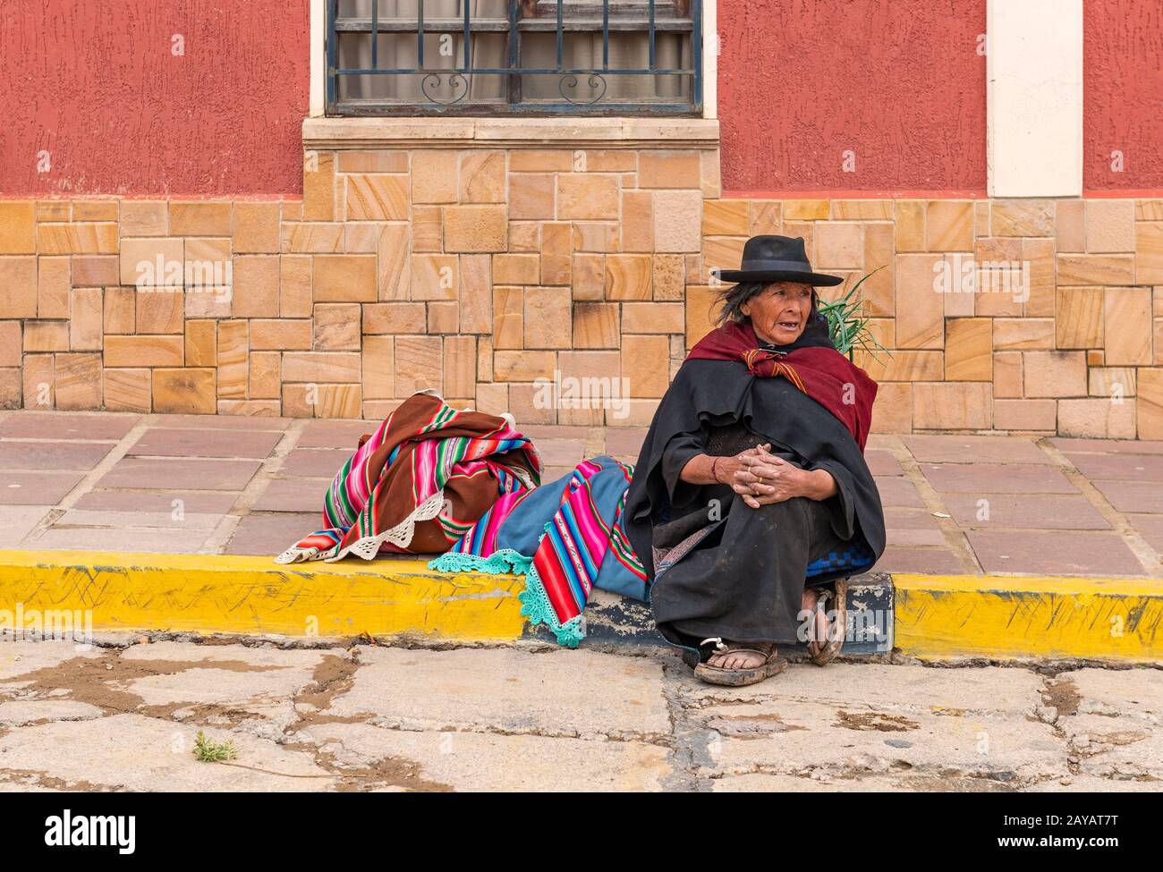 Indigenous Tarabuco lady with traditional clothing sitting on the sidewalk by the local market, region around Sucre, Bolivia. Stock Photo