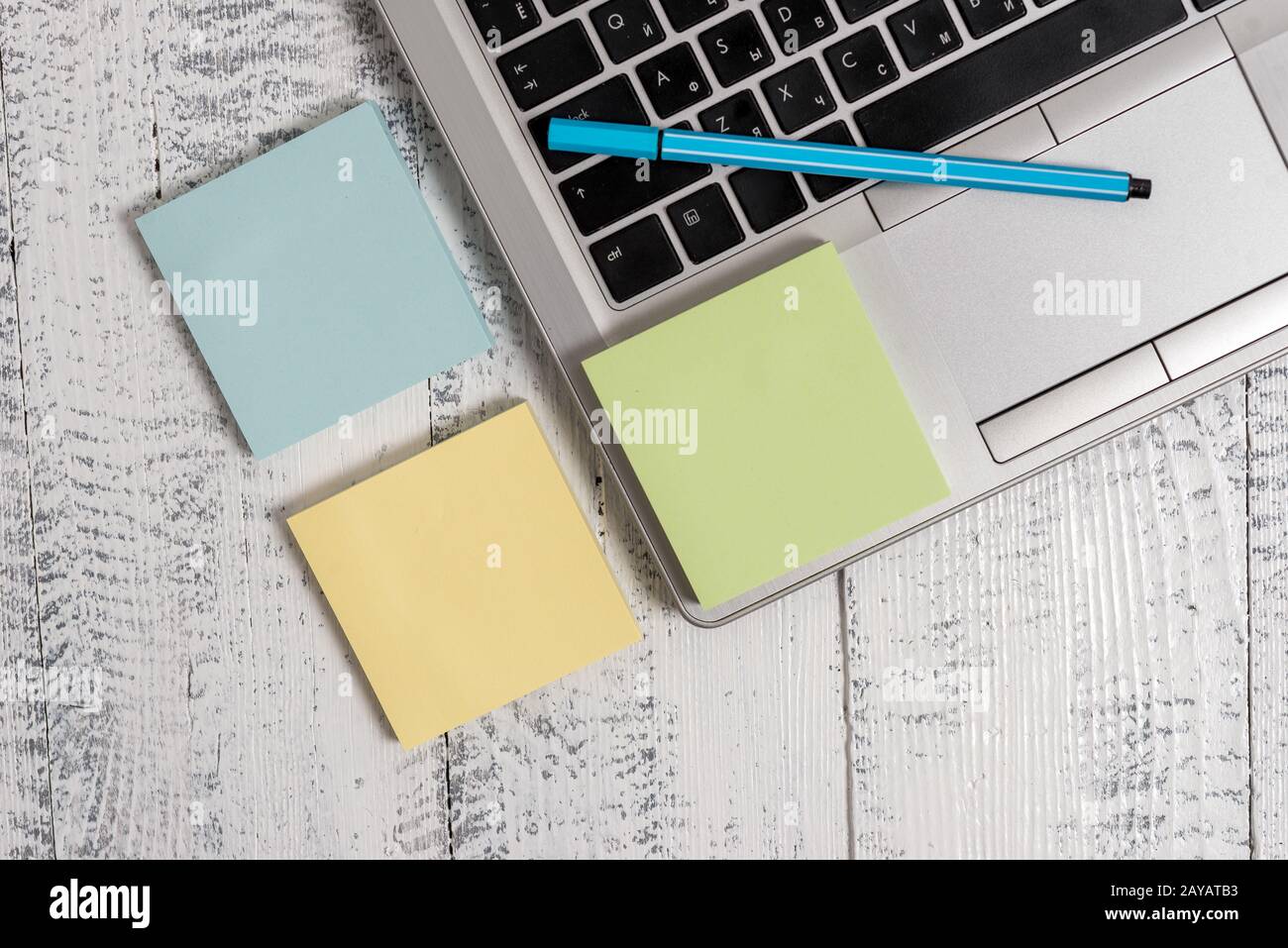 Trendy metallic laptop three sticky note pads pen ballpoint lying wooden rustic vintage table