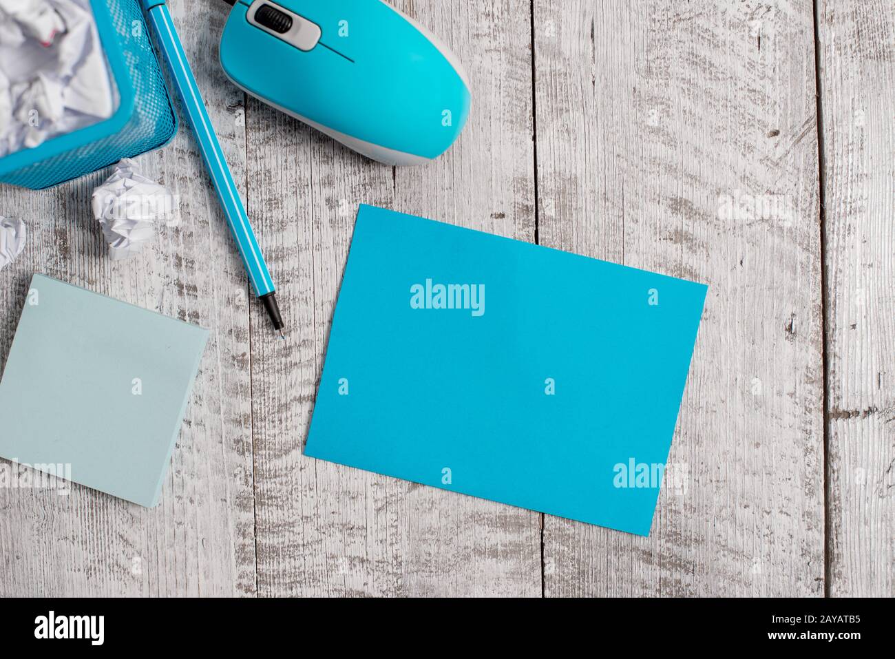 Crumpled paper and computer mouse with stationary placed above wooden table. Empty cardboard
