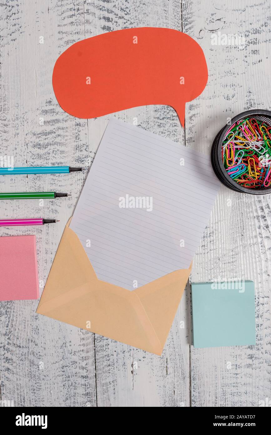 Front view open envelop speech bubble paper sheet ballpoints notepads clips holder lying wooden old retro vintage rustic backgro Stock Photo