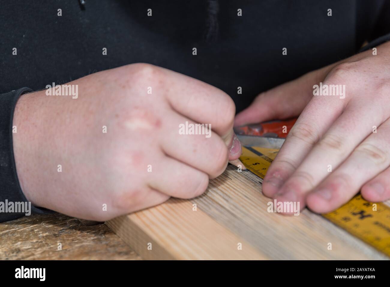 Carpenter measures wood with angle ruler and marks interfaces - close-up Stock Photo