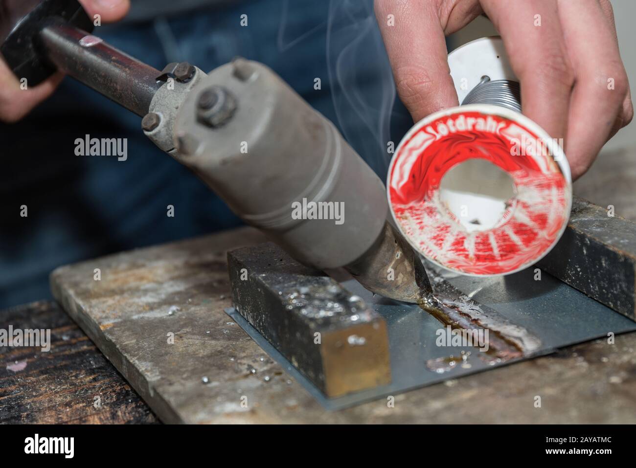 Manual worker learns to solder with soldering iron and solder wire - close-up Stock Photo