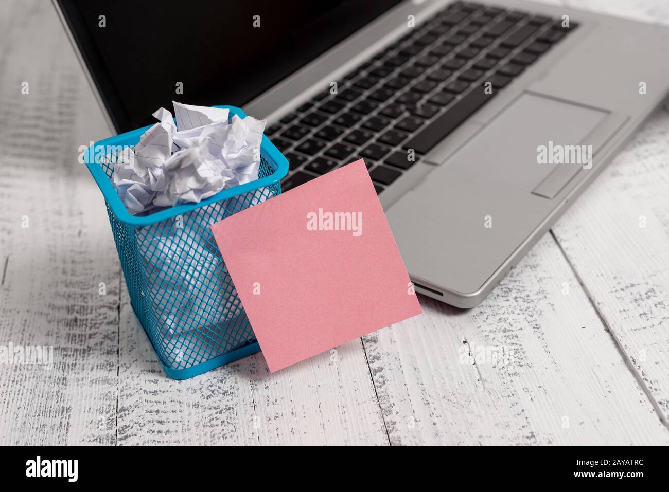 Trendy metallic laptop sticky note pad waste basket crushed paper lying wooden rustic vintage