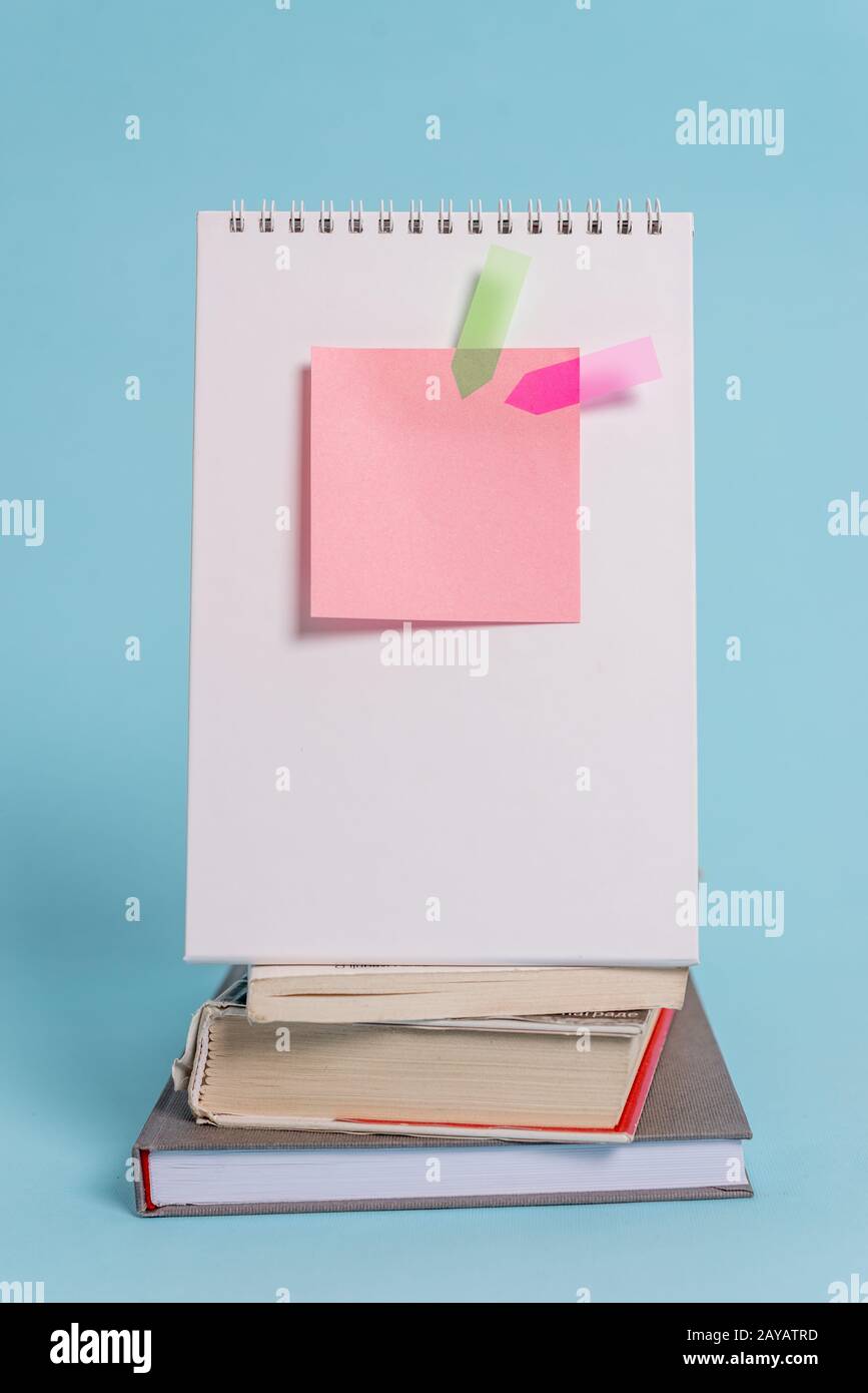 Stacked piled books standing spiral notebook sticky note arrow banners lying peaceful cool pastel background. Empty text future Stock Photo