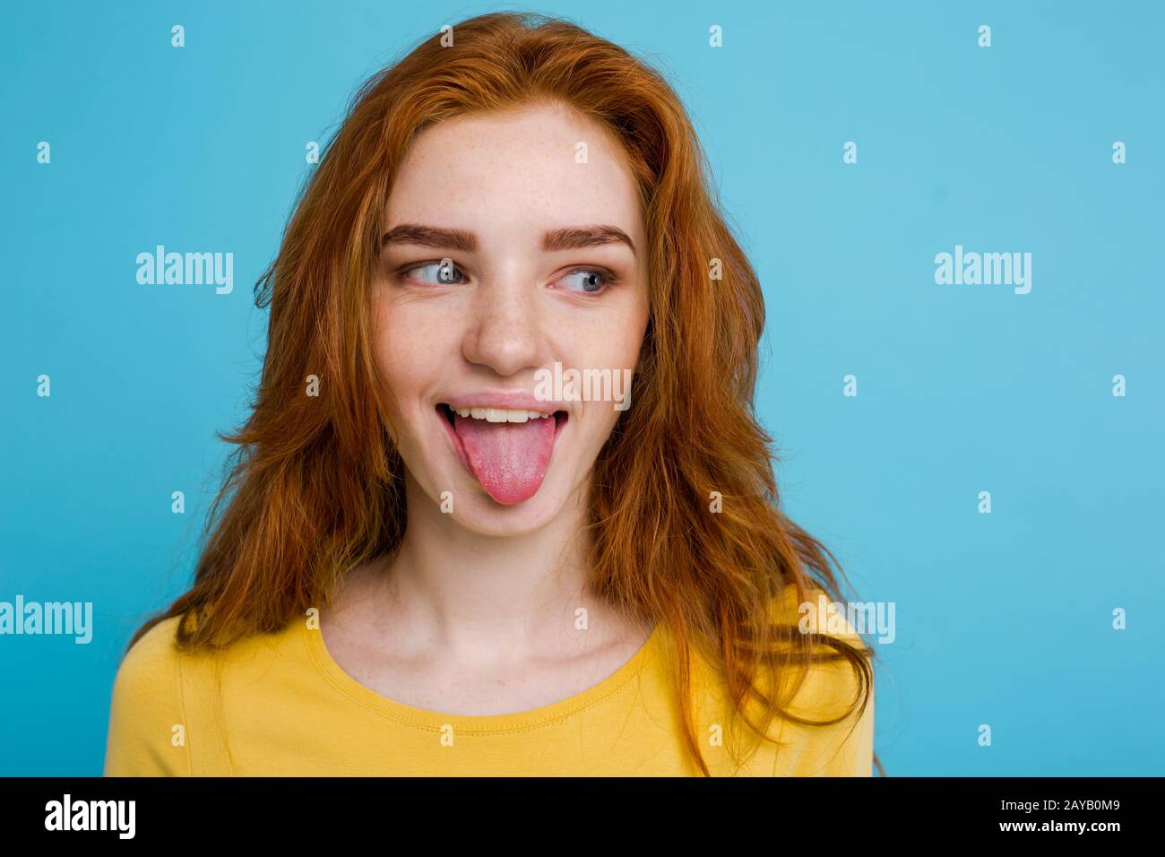 Headshot Portrait Of Happy Ginger Red Hair Girl With Funny Face Looking At Camera Pastel Blue