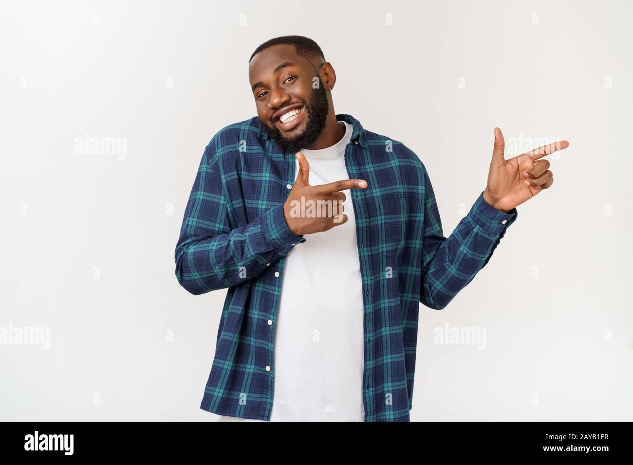 Happy delighted male fore finger at blank copy space, wears denim shirt, has positive smile. Advertisement and ethnicity concept Stock Photo