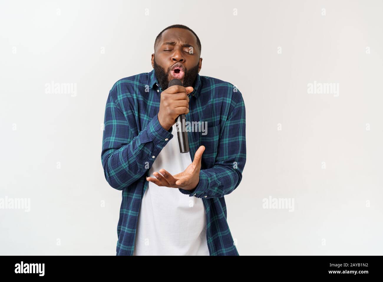 Portrait of cheerful positive chic handsome african man holding microphone singing song. Isolated on white background. Stock Photo