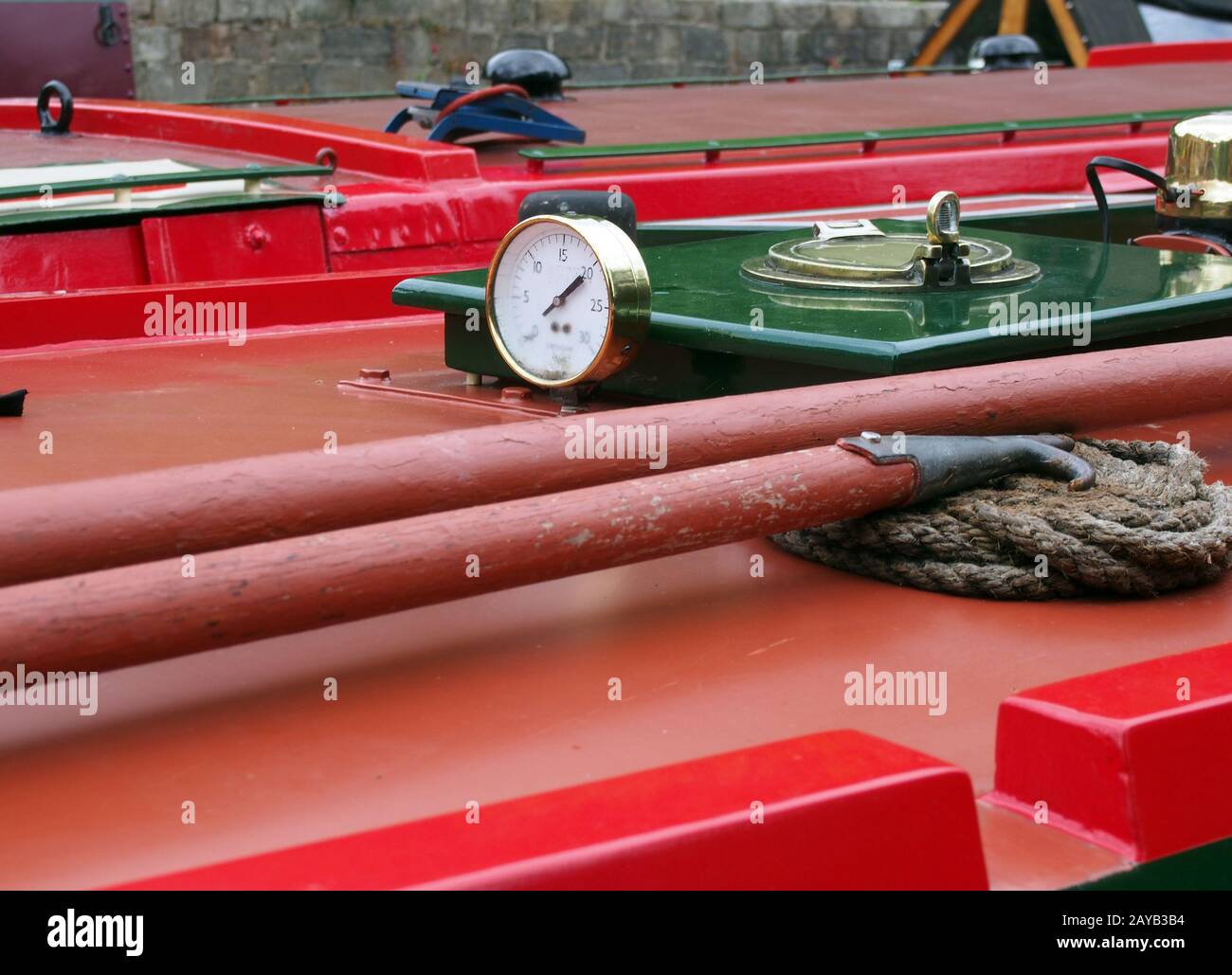 a close up of a brass gauge porthole boathooks and ropes on an old red ...