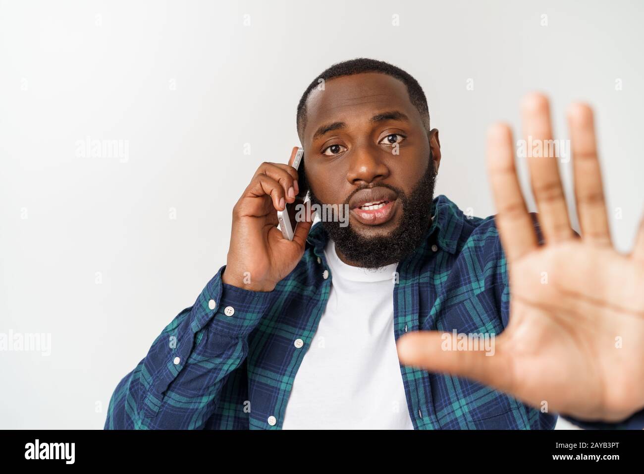 A young African American man talking on his cellular phone with a concerned or serious look on his face Stock Photo