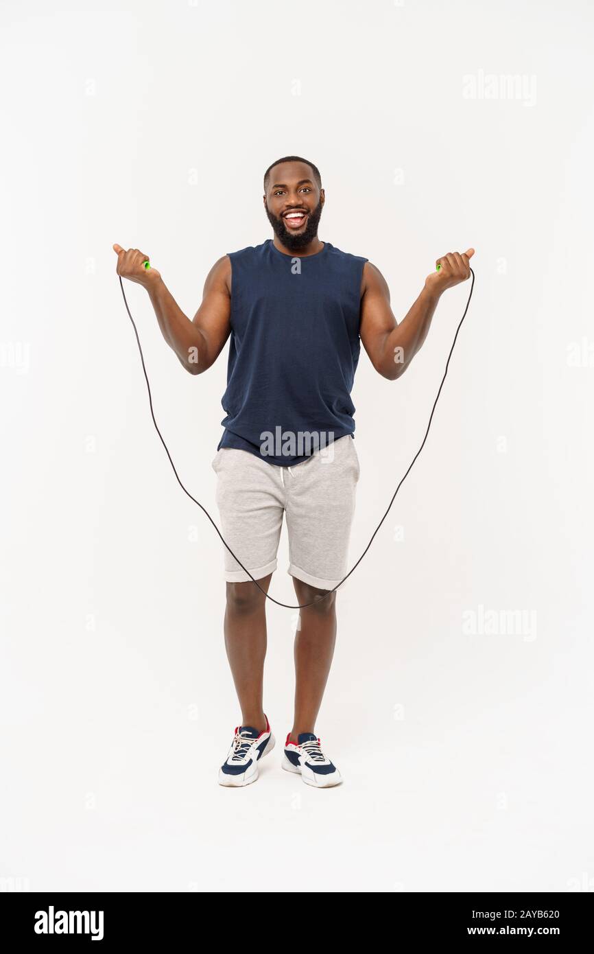 Shot of masculine man skipping rope. Muscular young man exercising with jumping rope against grey background Stock Photo
