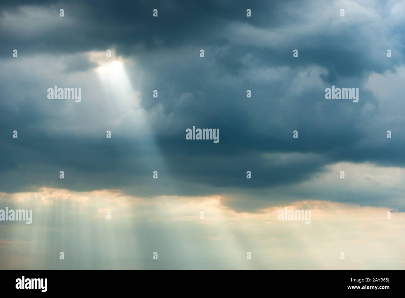 Dramatic storm sky with dark clouds and bright sunbeams Stock Photo