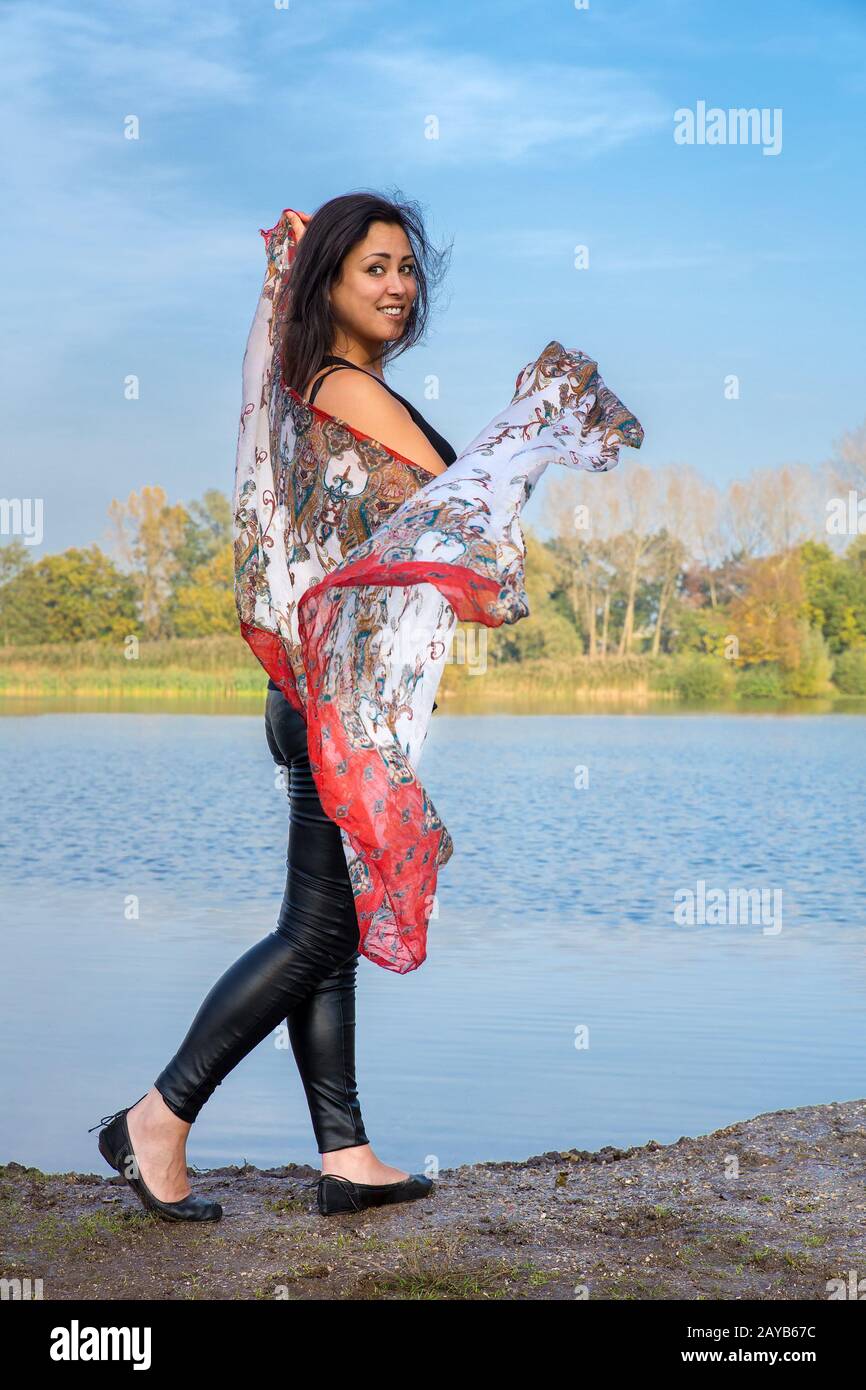 Woman showing colorful shawl at water Stock Photo
