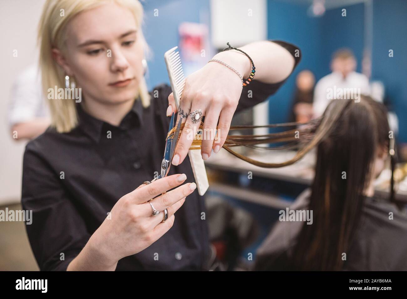 hairdresser holding scissors and comb and makes haircut woman client