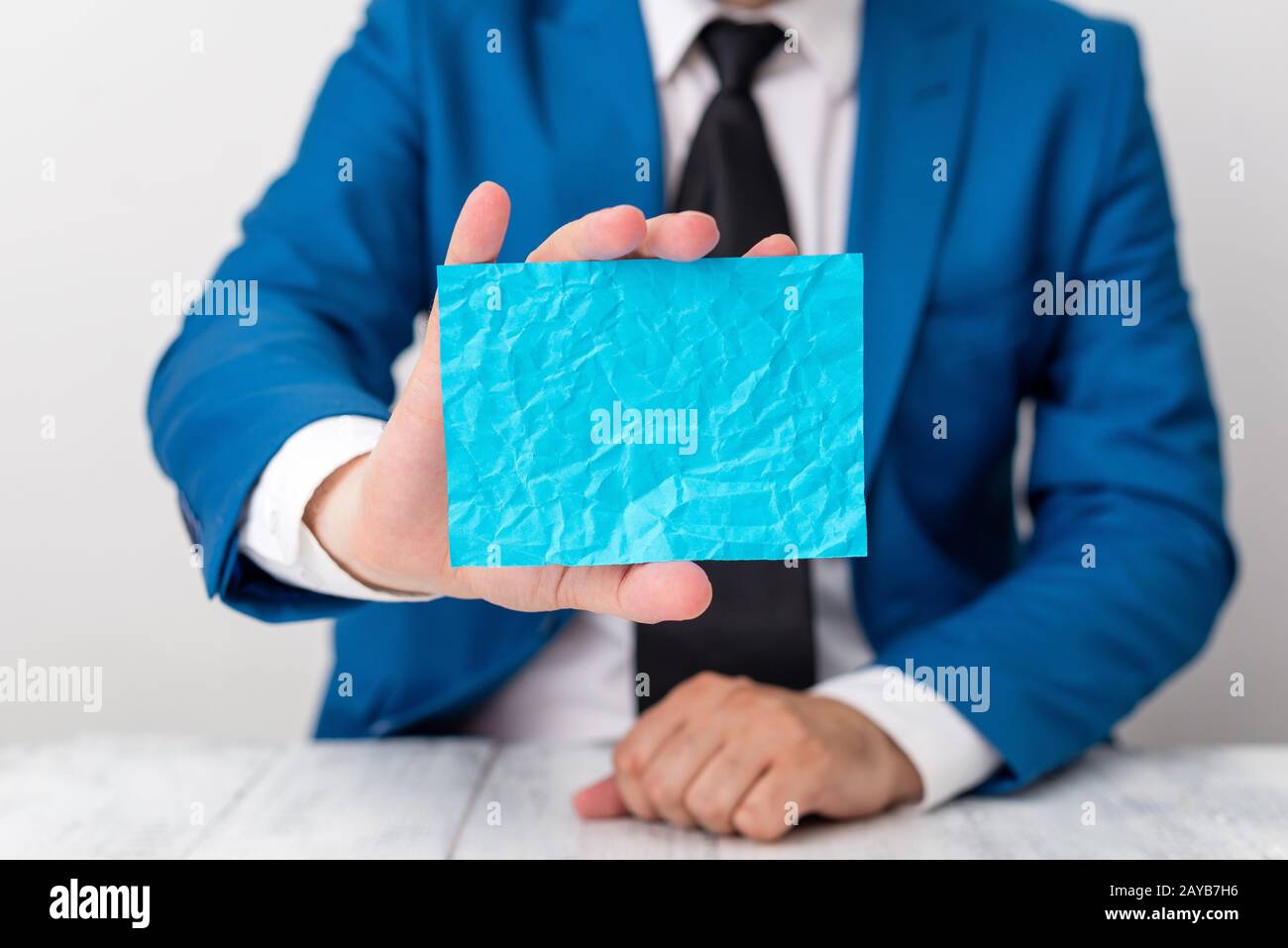 Man holds empty blue paper with copy space in front of him. Business concept with man in a suite and a tie. Blue space for adver Stock Photo