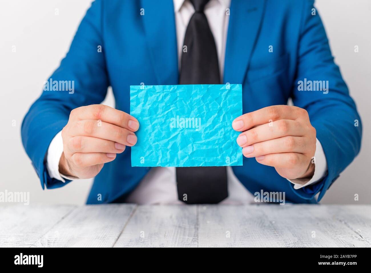 Man holds empty blue paper with copy space in front of him. Business concept with man in a suite and a tie. Blue space for adver Stock Photo