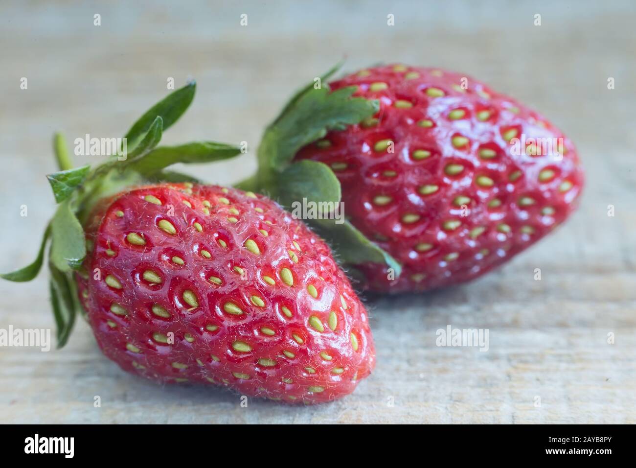 Two strawberries on the surface of the wooden table. Stock Photo