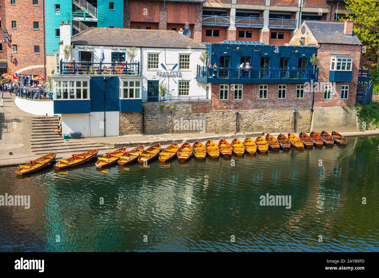 Line of moored rowing boats on the banks of River Wear near a boat club in Durham, United Kingdom on a beautiful spring afternoo Stock Photo