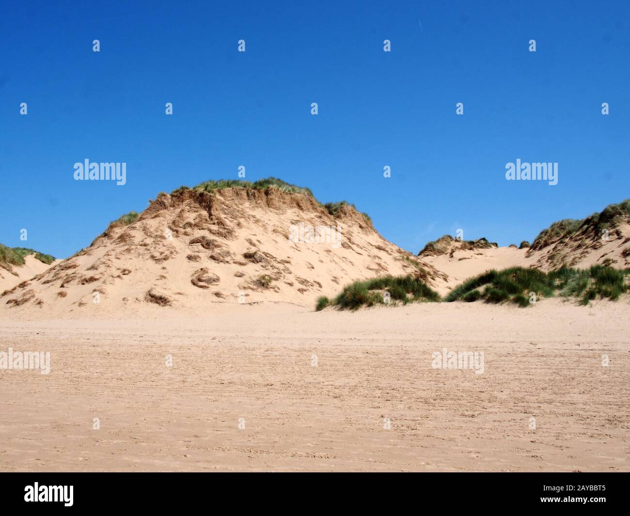 the beach at formby merseyside with tall sand dunes covered in rough grass and a blue summer sunlit sky Stock Photo