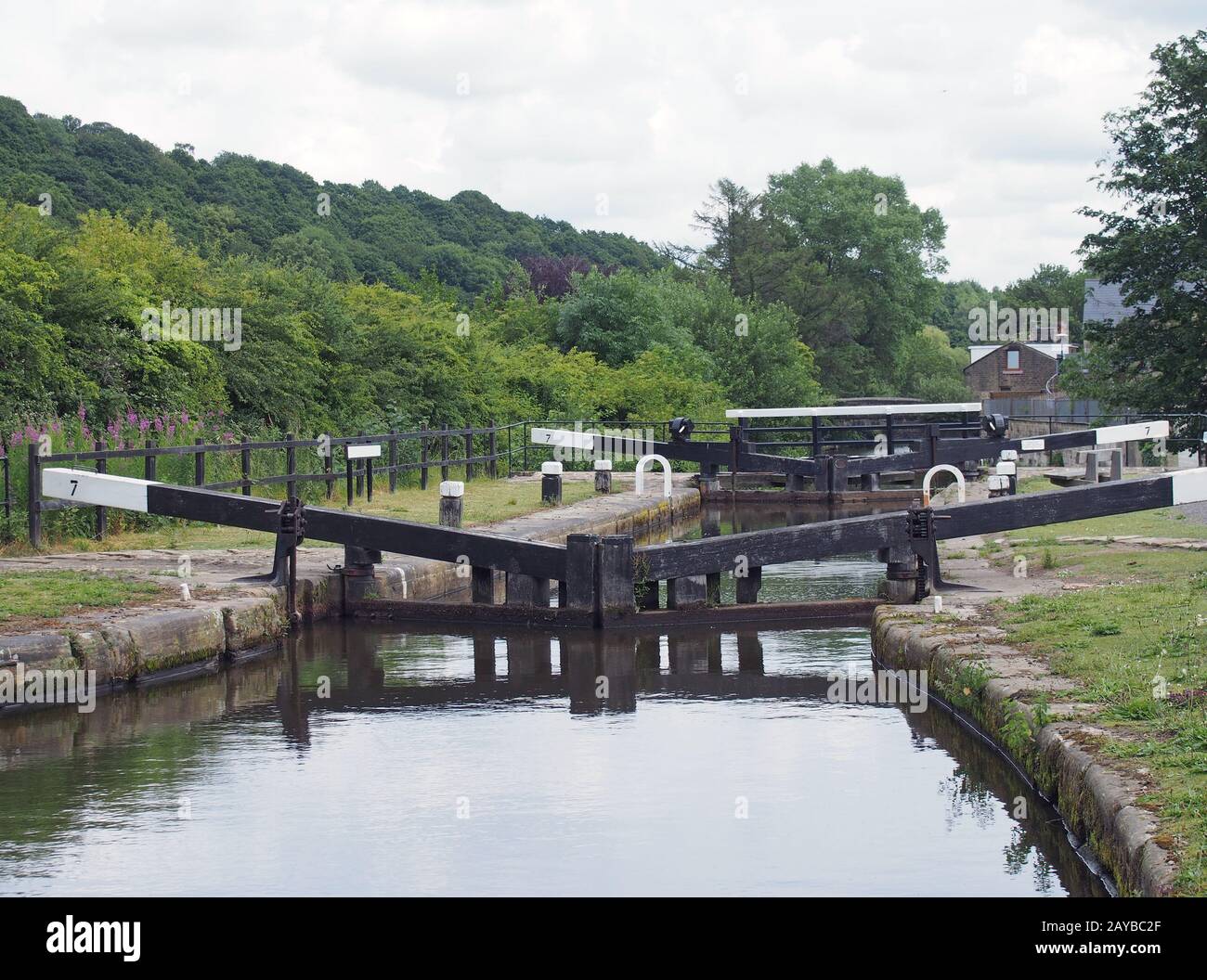 broadbottom lock on the rochdale canal on the outskirts of mytholmroyd west yorkshire with summer trees lining the valley and bu Stock Photo
