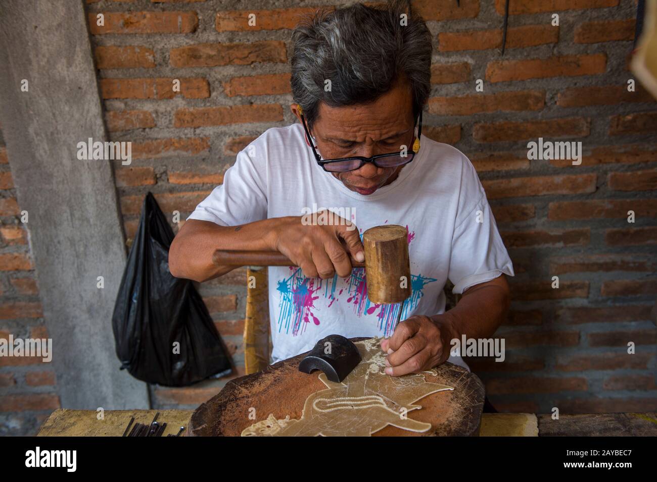 A man is making traditional Javanese wayang kulit (shadow puppet) out of leather in Yogyakarta, Java, Indonesia. Stock Photo