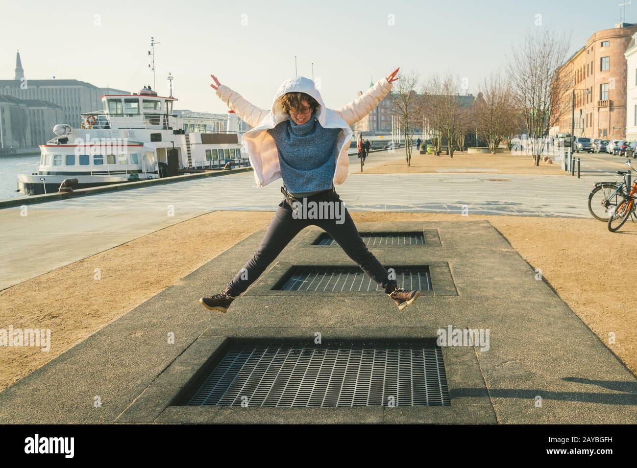 adult person rejoices like child. Playground trampoline in ground, children trampoline, springs throws people up fun and cool. C Stock Photo
