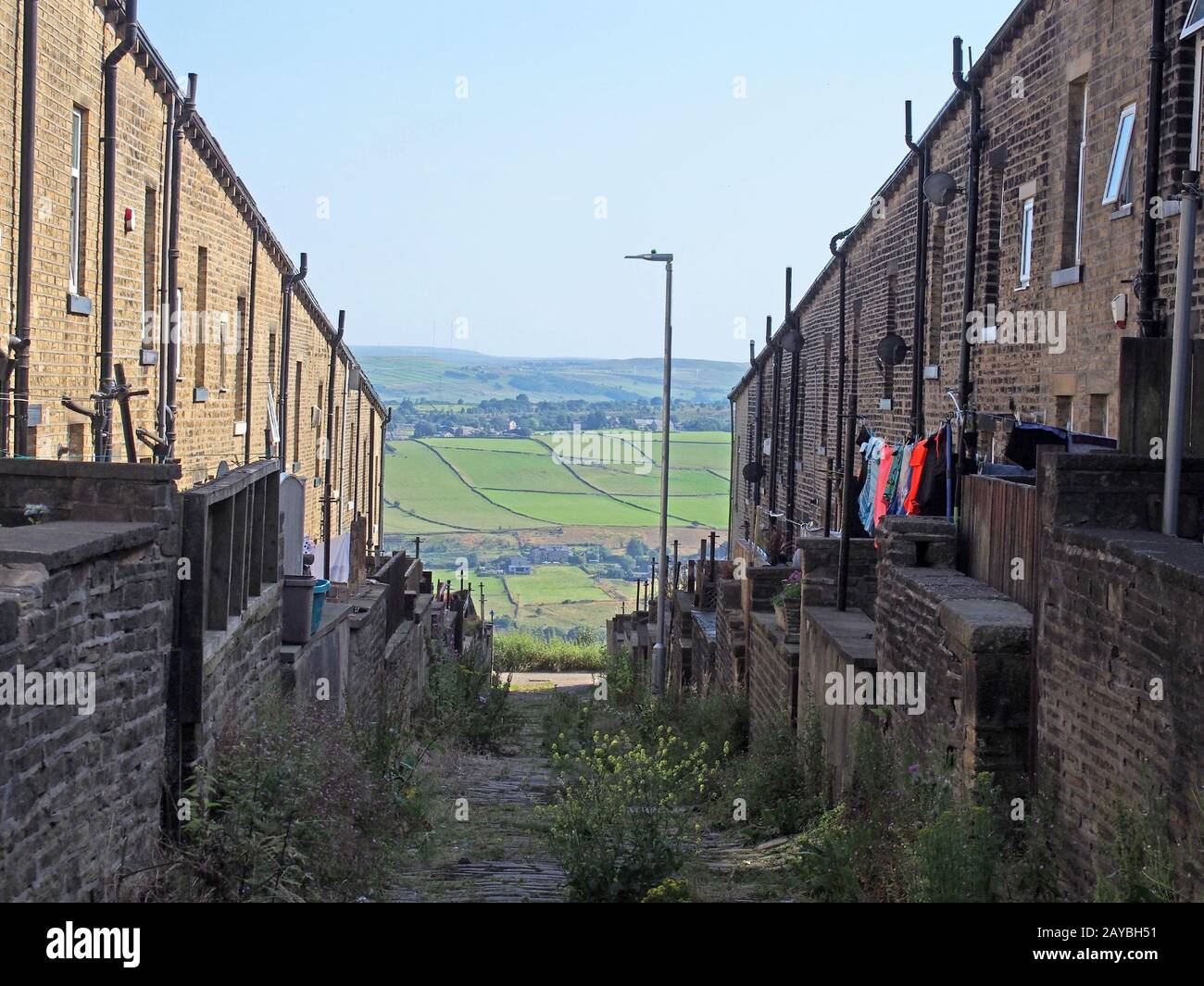 a typical northern back alley in west yorkshire with yards and washing lines between streets of old houses with a view of fields Stock Photo