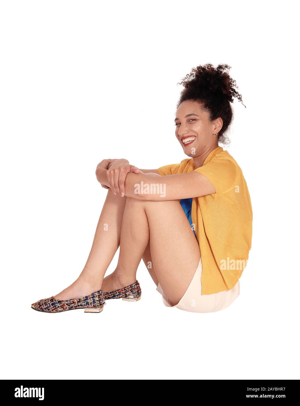 Beautiful young multi-racial woman sitting on floor and smiling Stock Photo