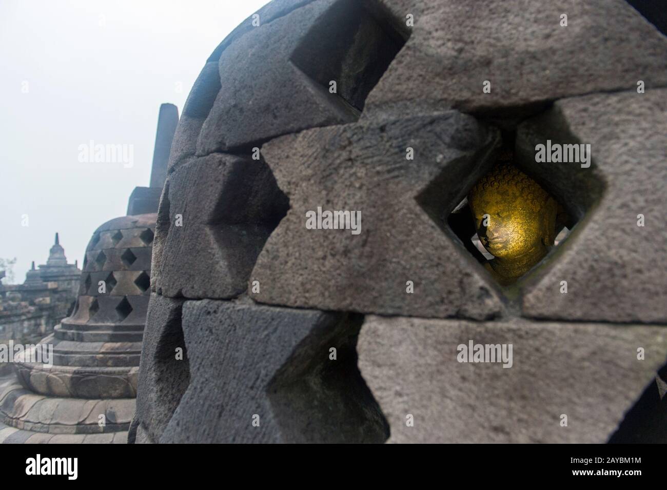 View of a Buddha statue inside a perforated stupa on the upper platform of Borobudur temple (UNESCO World Heritage Site, ninth-century), the largest B Stock Photo