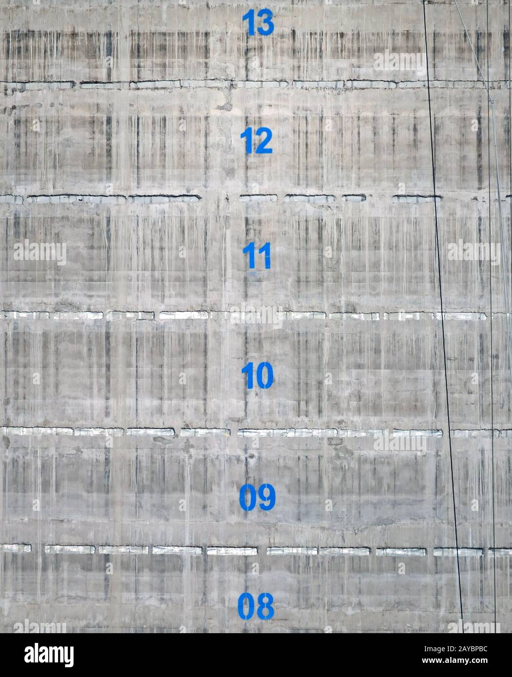 the surface of a concrete service tower core of a building under construction with the floor numbers marked in blue paint Stock Photo