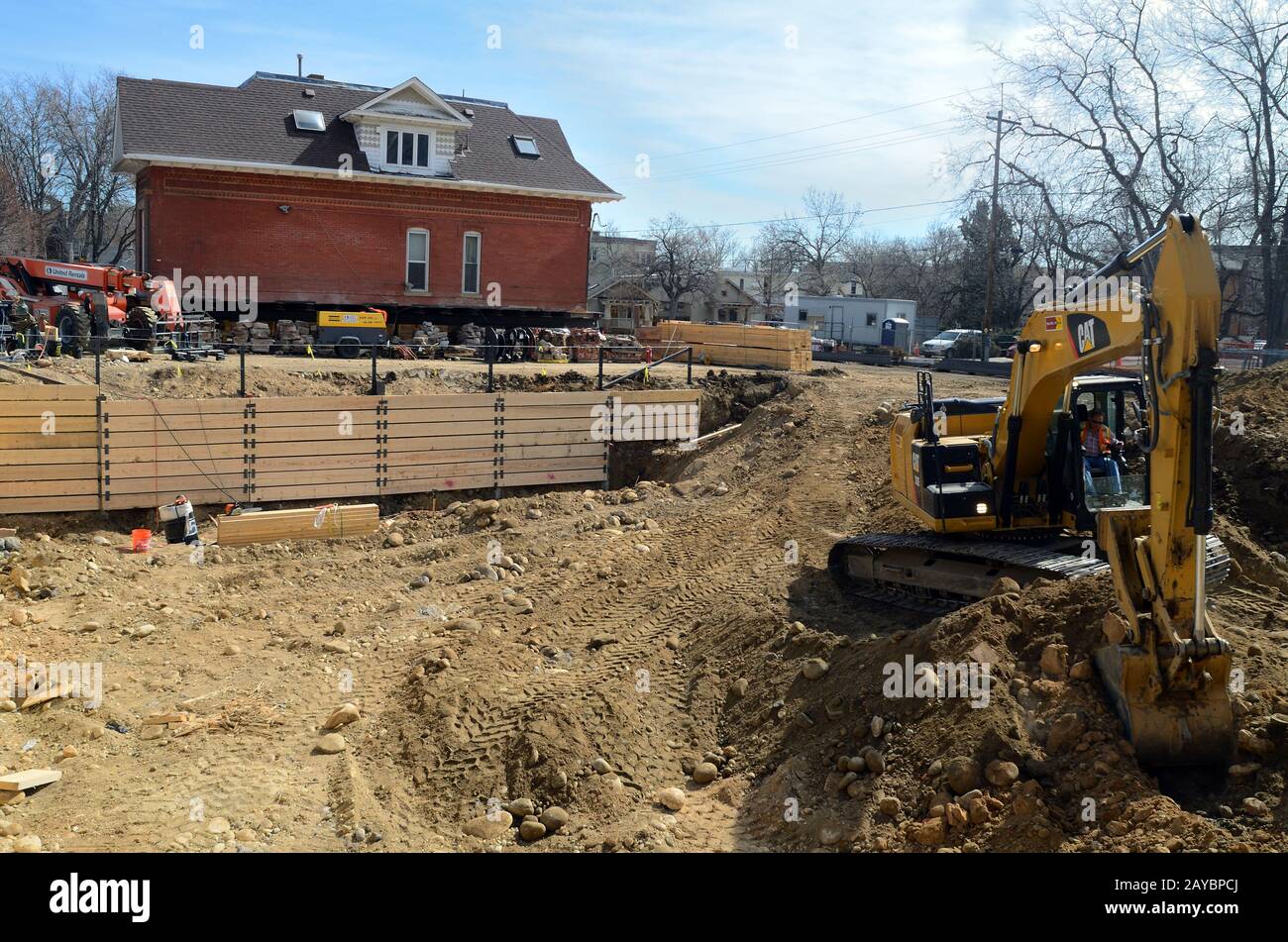 A small excavator digs a basement parking facility for Attention Homes new apartments for homeless young adults, ages 18 to 24. Stock Photo