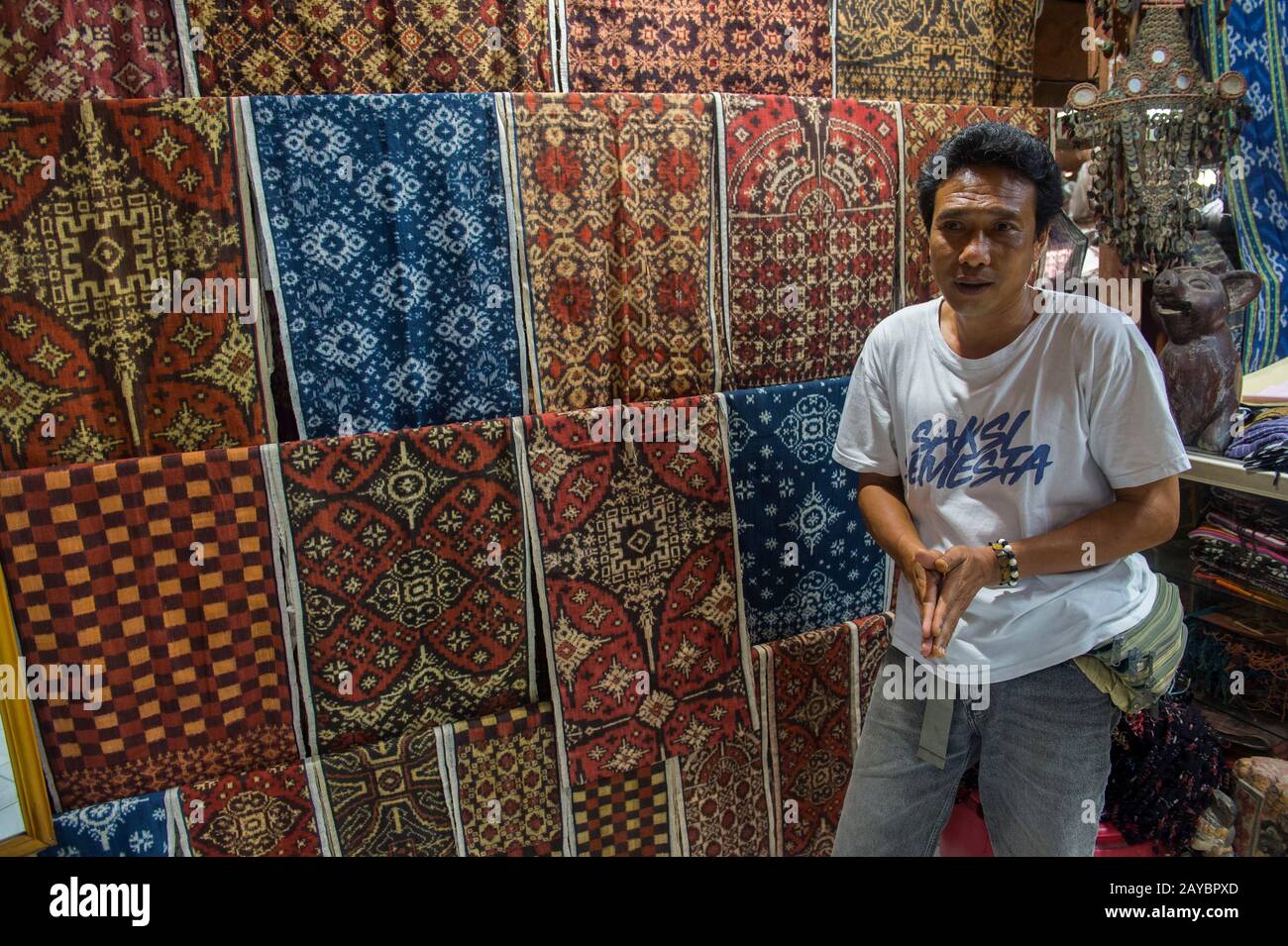 A man is explaining the double Ikat weaving in a house in the Tenganan