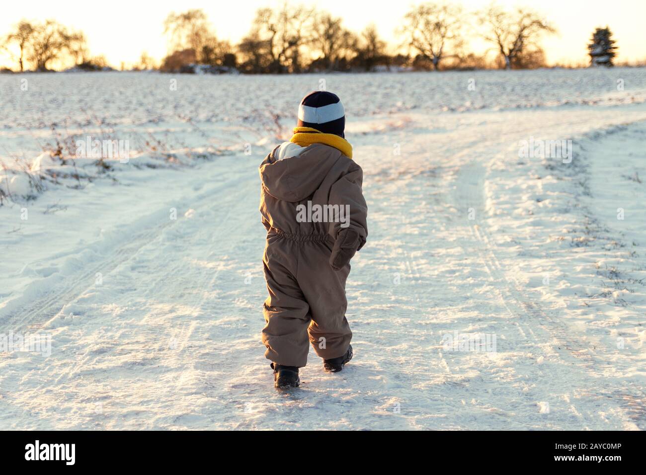 Little toddler walking outdoors in a snowy winter scene. Stock Photo