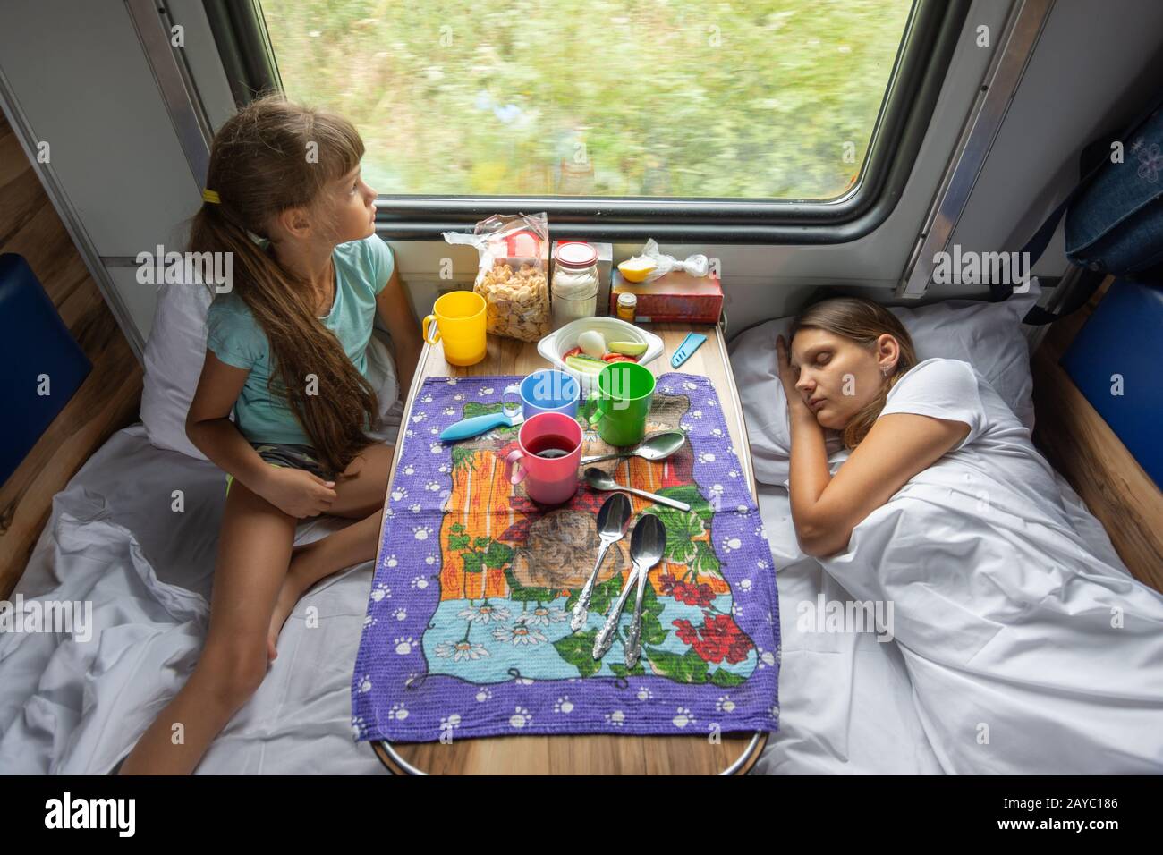 The situation on the train, mom is sleeping, daughter is looking out the window, top view Stock Photo