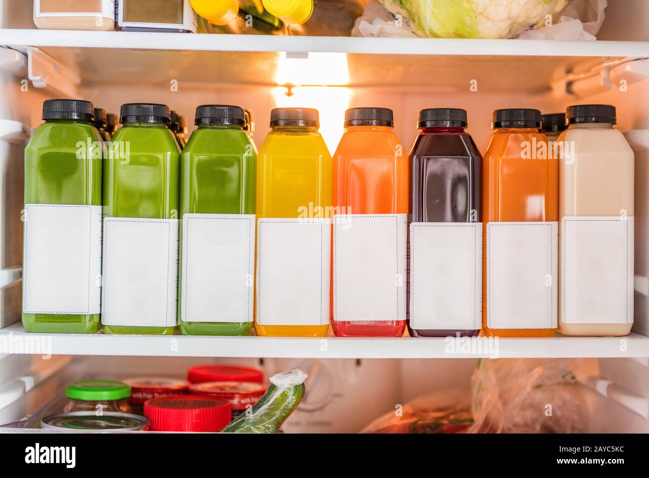 Juicing cold pressed vegetable juices for a detox cleanse diet. Dieting bydrinking organic fruits and vegetables juice made fresh and delivered in bottles at home in fridge. Stock Photo