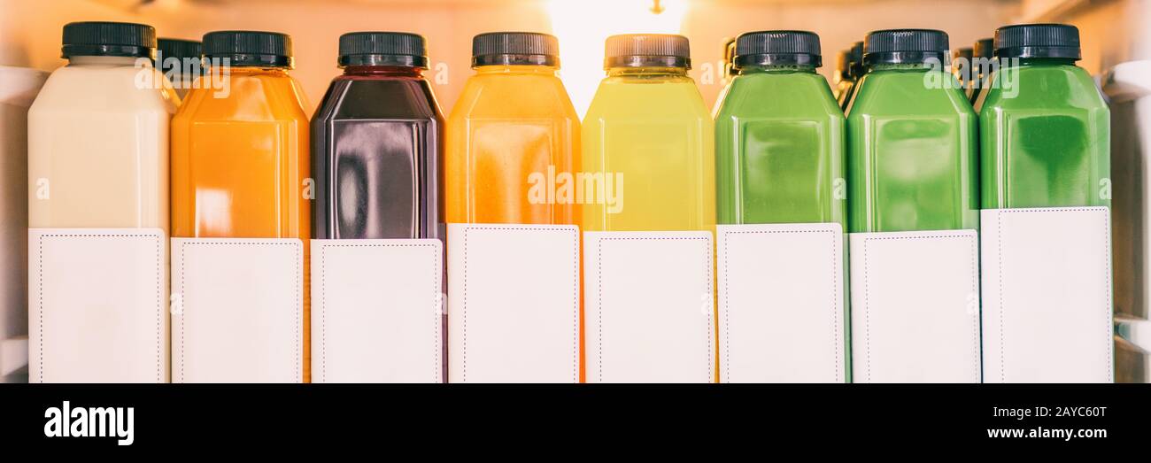 Juice bottles for detox cleanse juicing trend - Healthy diet food delivery at home in fridge banner panorama. Selection of cold press vegetable and fruit juices, orange, lemon, beets, spinach. Stock Photo