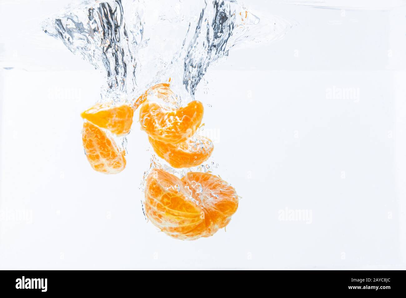 Isolated falling orange segments into water. Peeled pieces of orange