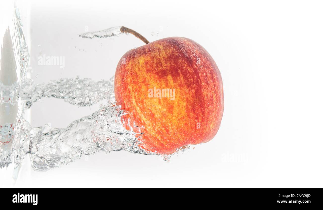 Apple falls under water with a splash from left side Stock Photo