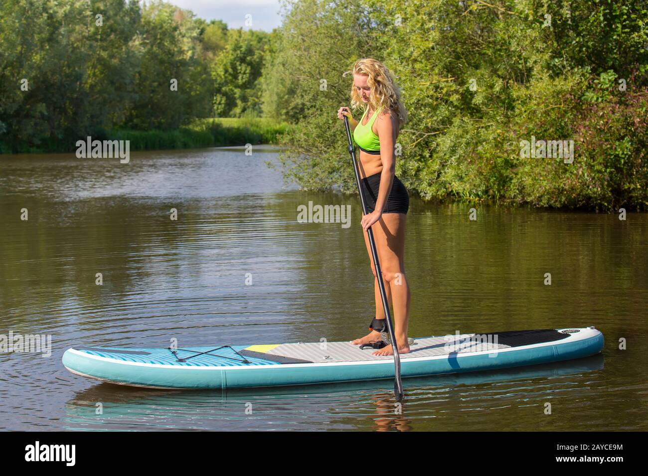 Standing caucasian woman paddling with SUP Stock Photo