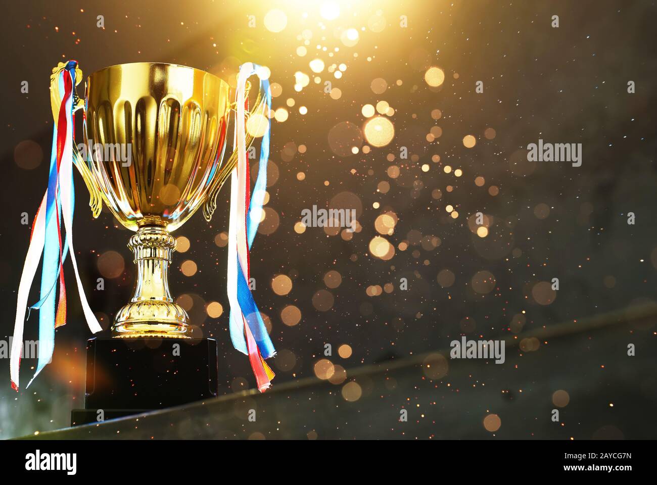 Low key golden trophy on the blur gray background with abstract shiny lights . Stock Photo
