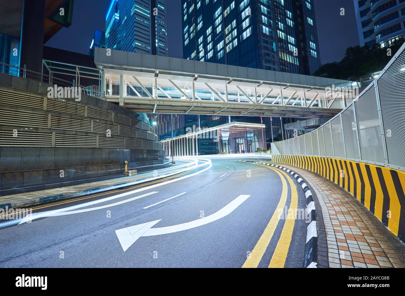 Empty asphalt city street road with walkway bridge and light trail Stock Photo