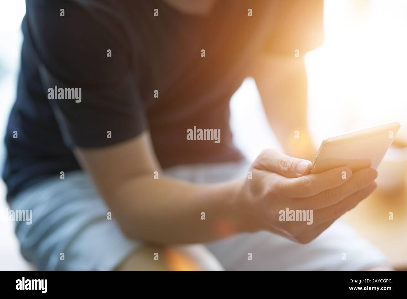 Closeup of young man using smartphone with sun flare . Stock Photo