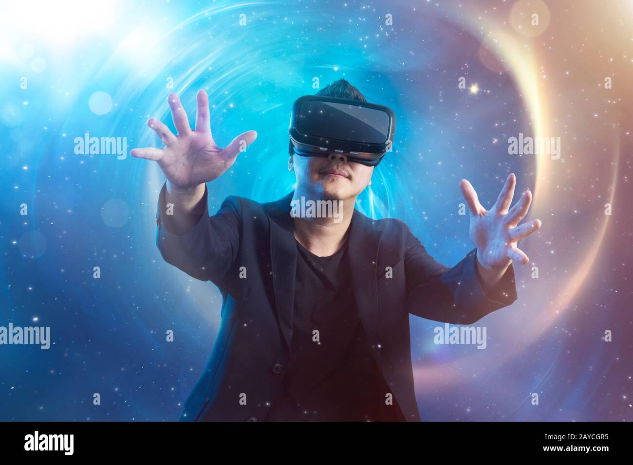The young man wearing virtual reality goggles with amazing cosmic futuristic space virtual imaging background . Stock Photo