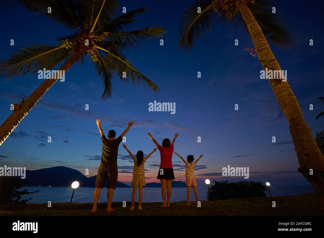 The family raised their hands and cheered to enjoy the seaside at dusk Stock Photo