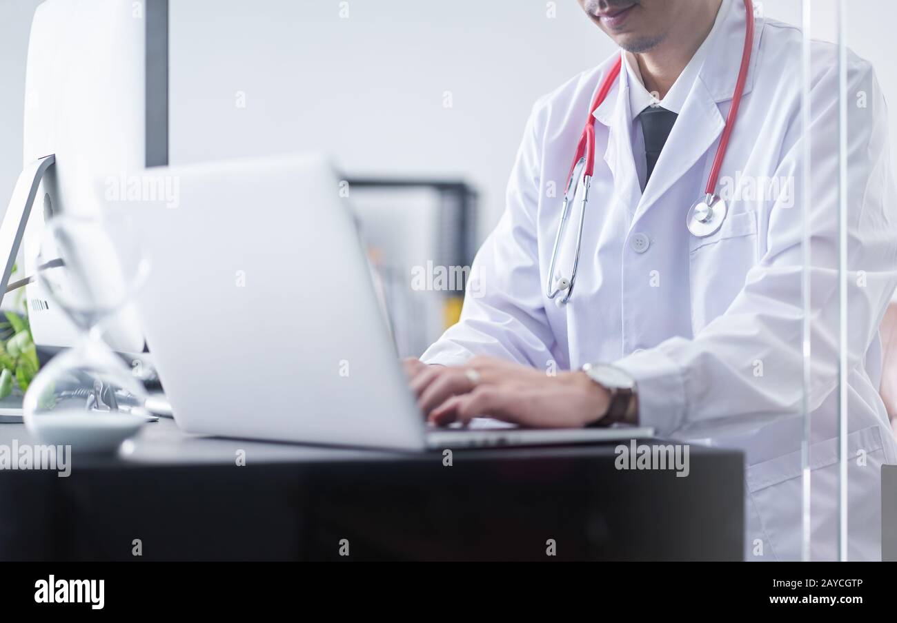 Young asian doctor sit and hard work with computer Stock Photo