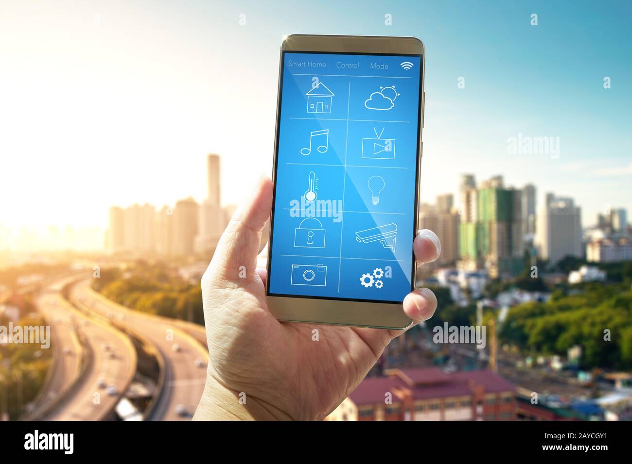 Smart remote home control system apps on a hand phone with out of focus cityscape background. Stock Photo