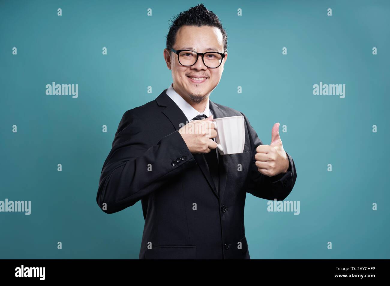 Businessman in suit smile and enjoy cup of coffee with thumb up gesture. Stock Photo