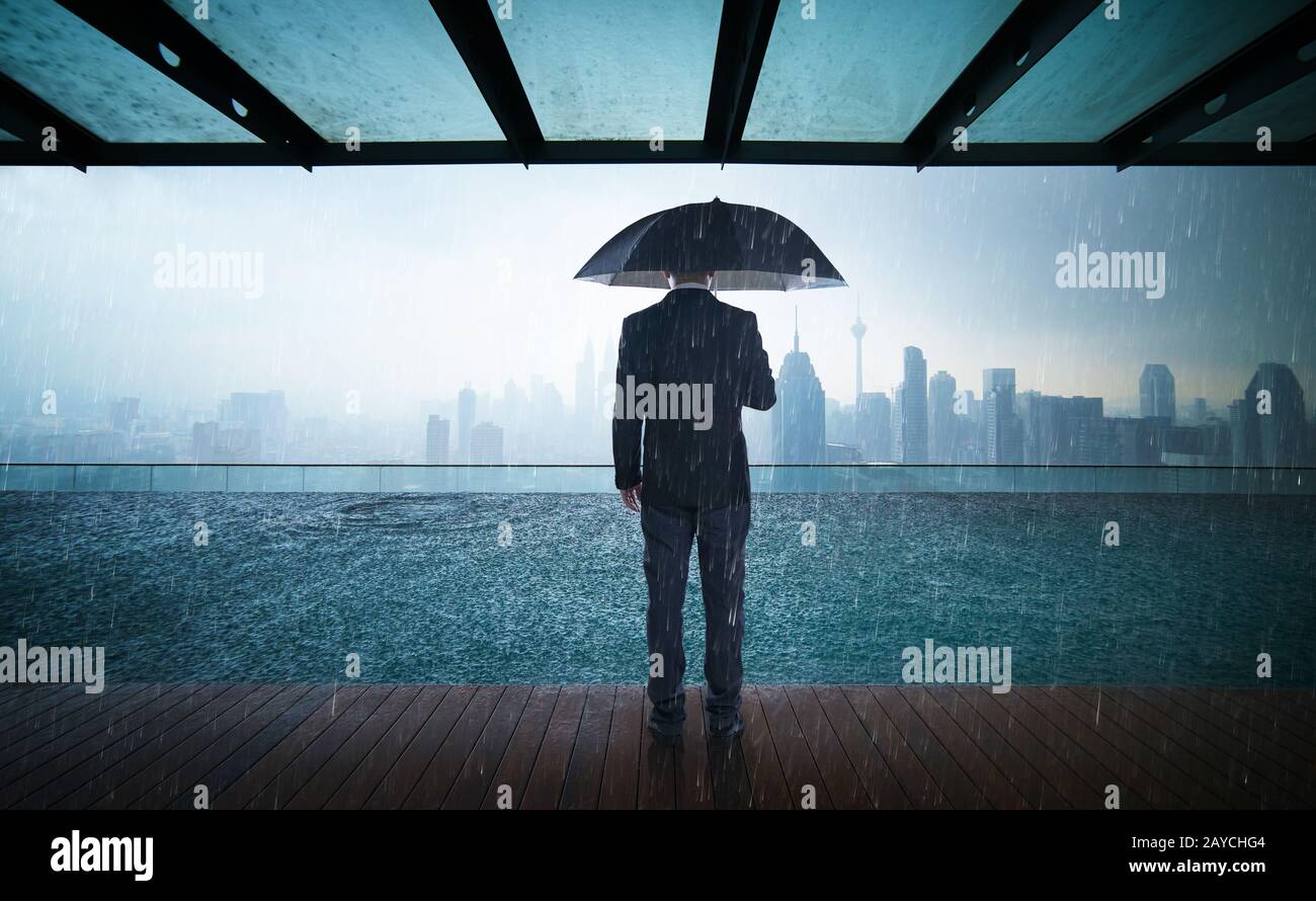 Businessman hold umbrella stand on rooftop Stock Photo