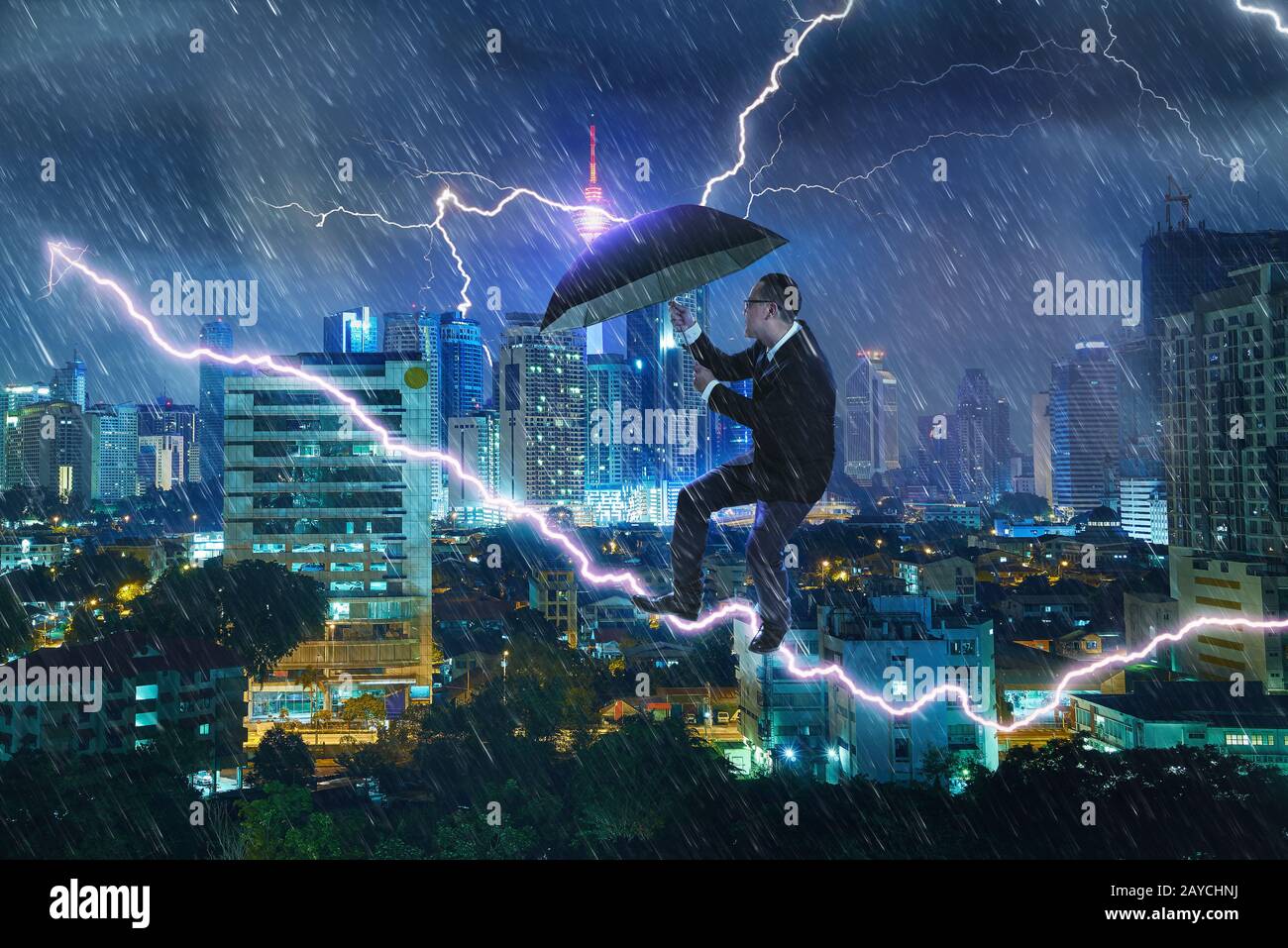 Young businessman with umbrella against thunderstorm.  Overcoming challenges and crisis concept. Mixed media Stock Photo